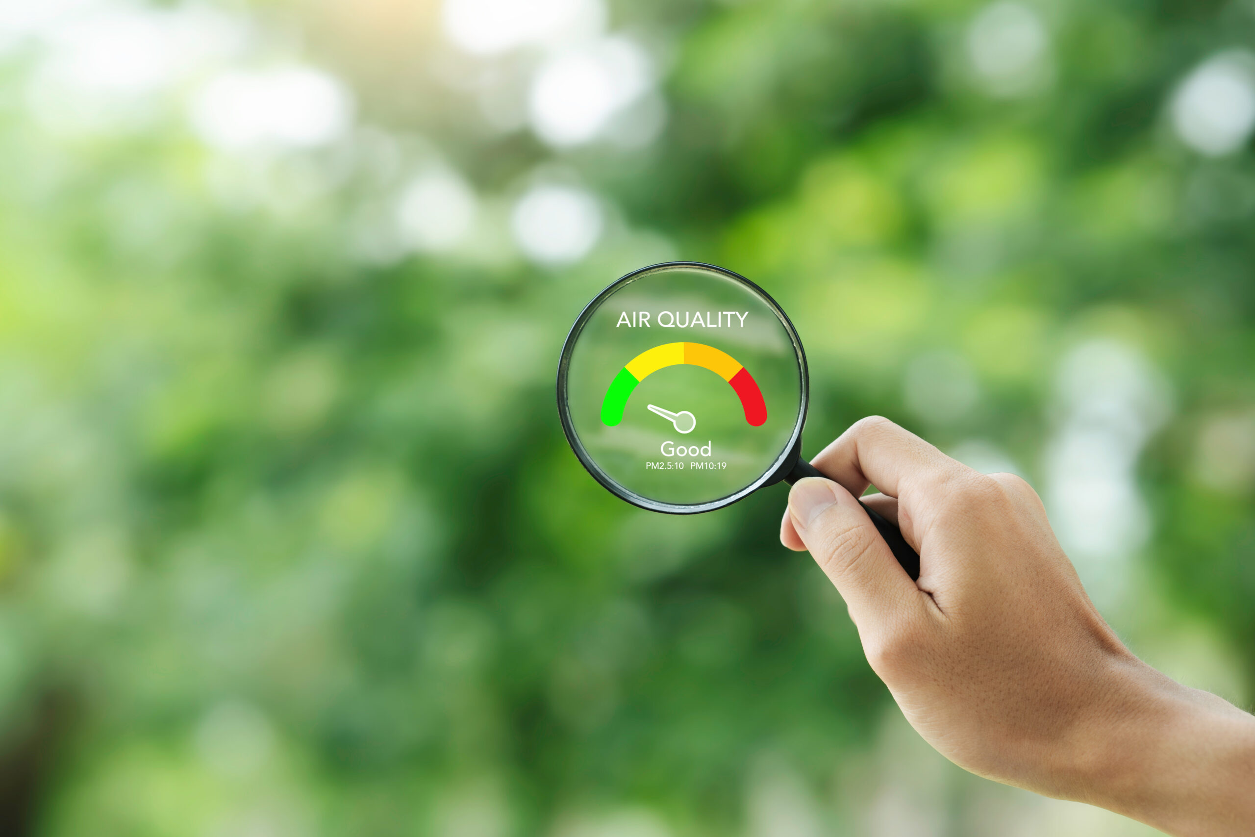 hand holding a magnifying glass to check the good air quality and clean outdoor air quality safe from pollution dust PM 2.5 checking air quality
